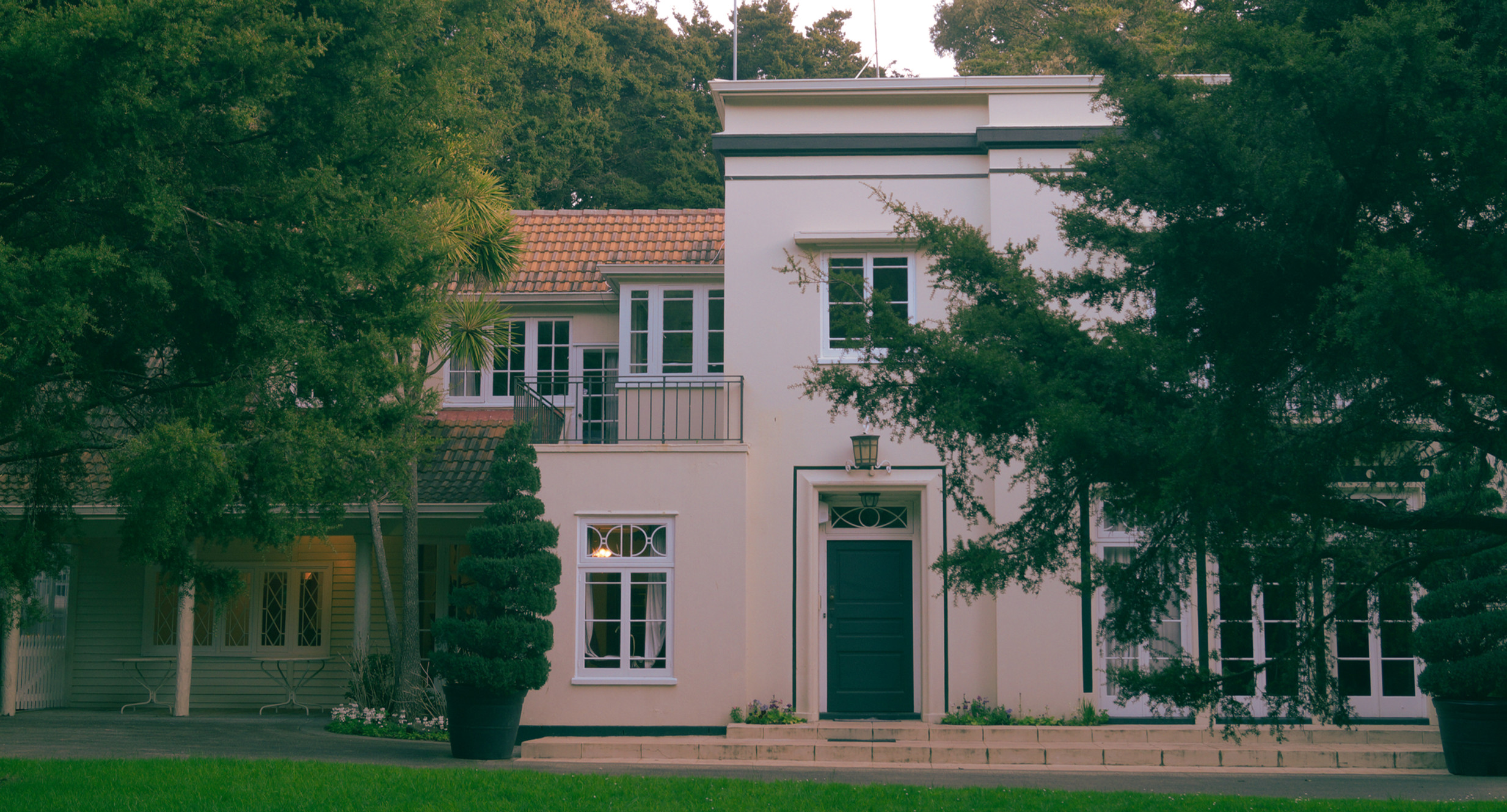 Two-storey rendered manor house with terracotta roof set among mature trees