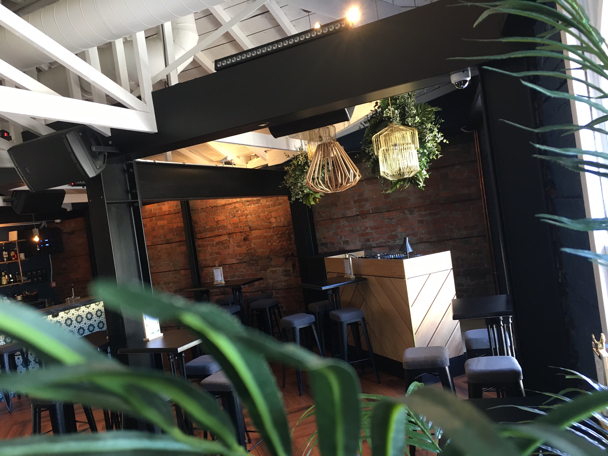 Dark industrial interior with exposed brick wall, hanging pendant lights, and bar stools