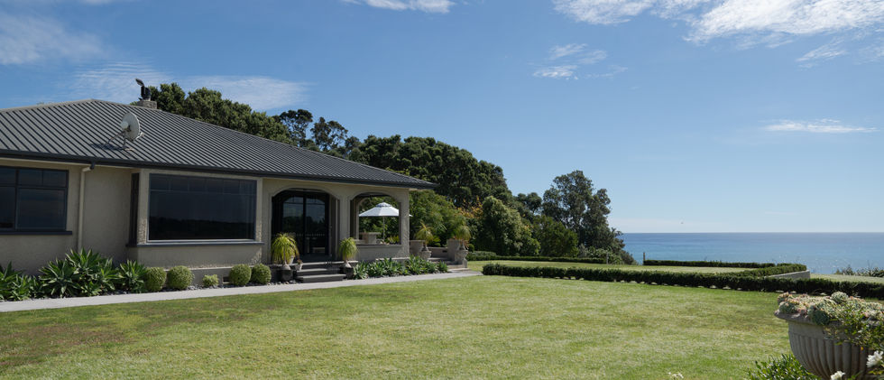 Low-rise venue building with arched entry and sea view from lawn