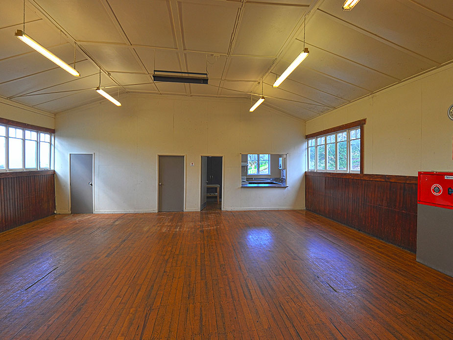Plain hall interior with timber-panelled walls, polished wooden floor and servery hatch