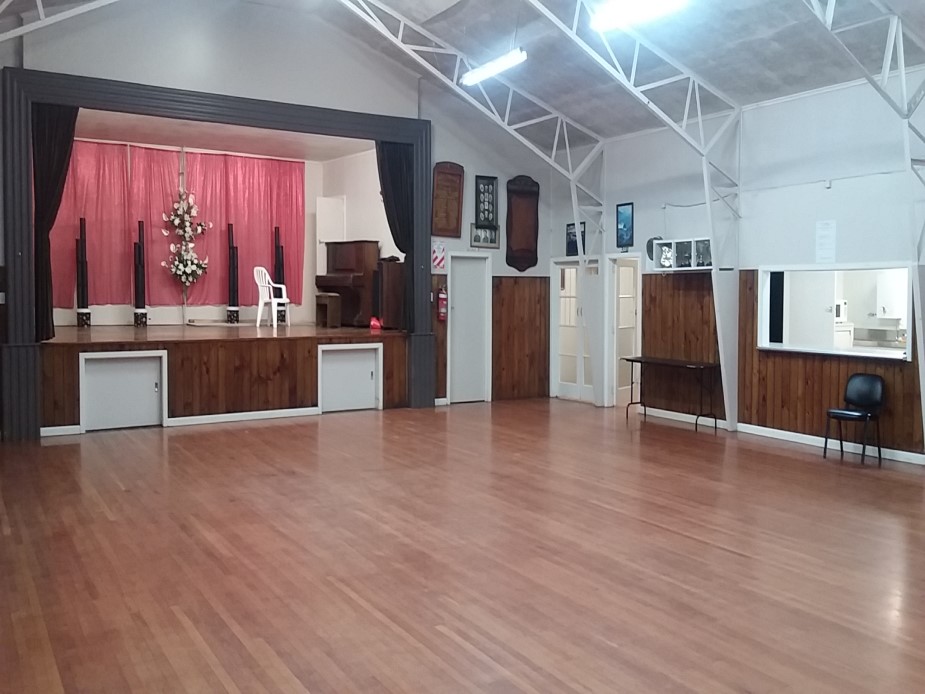 Hall interior with timber floor, raised platform with curtained surround and exposed roof trusses