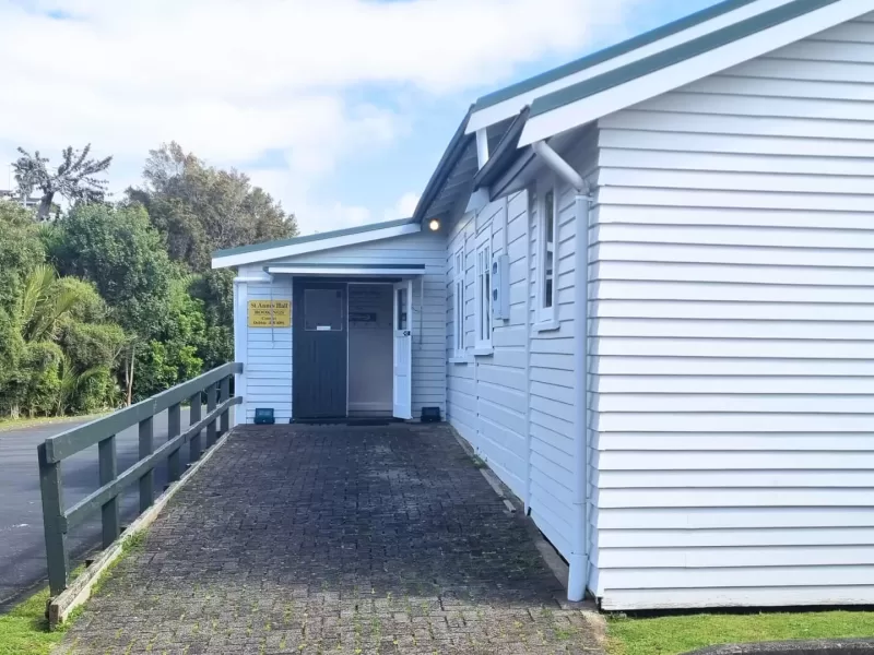Side entrance of white weatherboard hall with paved approach