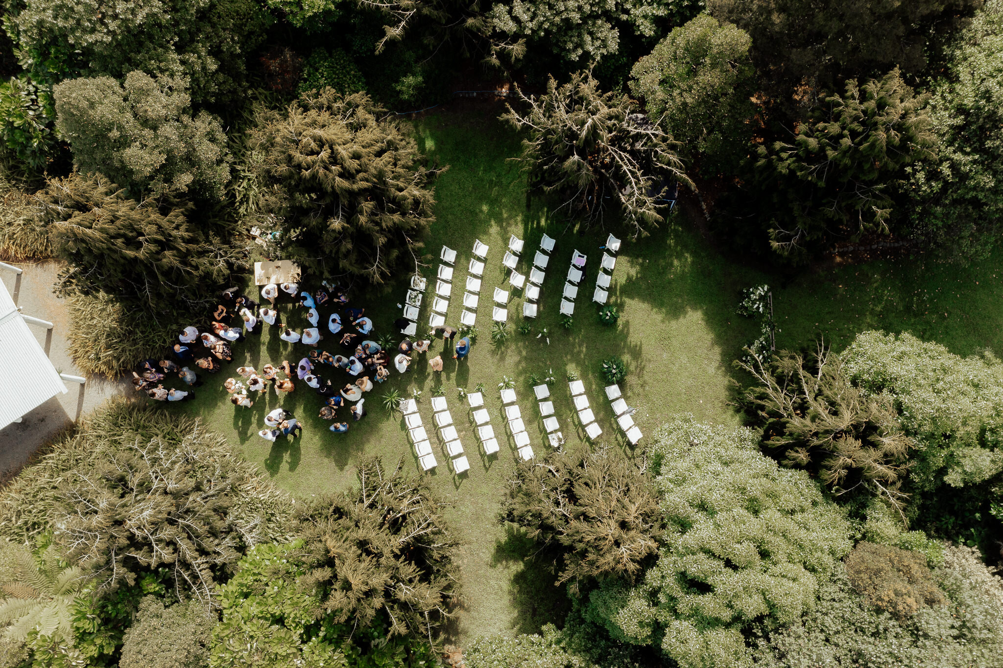 Aerial view of outdoor ceremony with white chairs set in rows and guests gathered on lawn