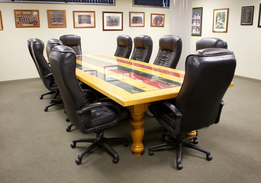 Boardroom with large timber table, leather chairs and sports memorabilia walls