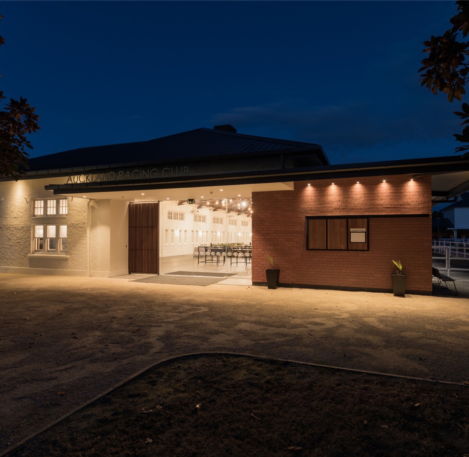 Low single-storey venue exterior lit at night with open doors revealing a set room