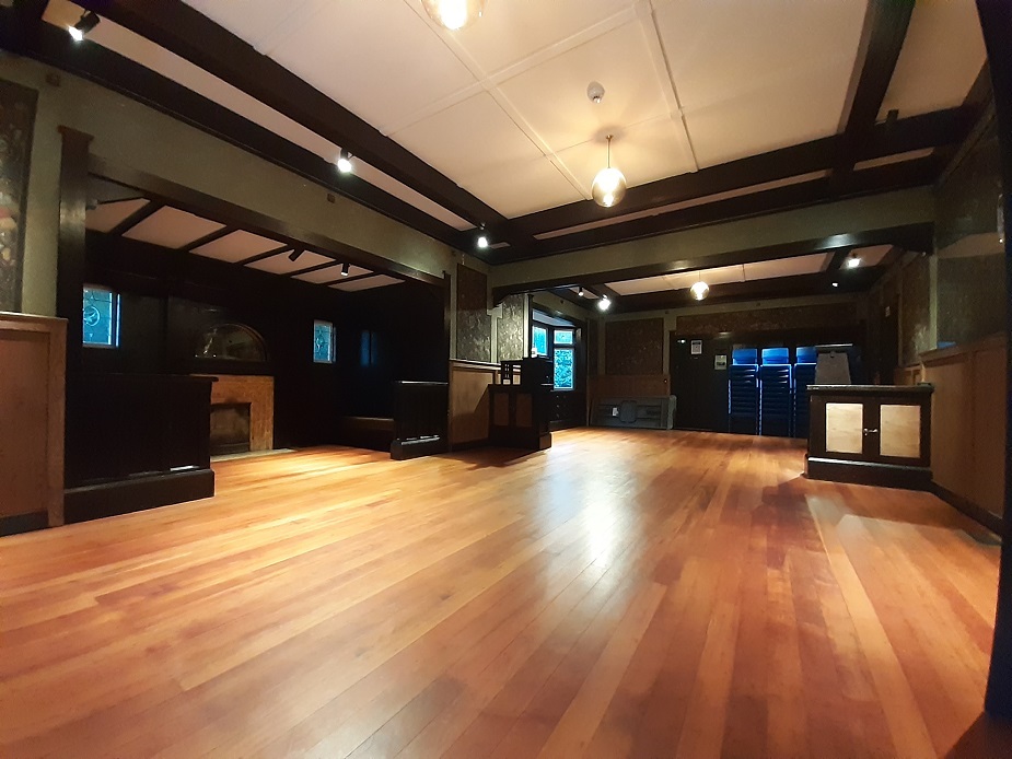 Dark-timbered hall interior with polished floor and fireplace