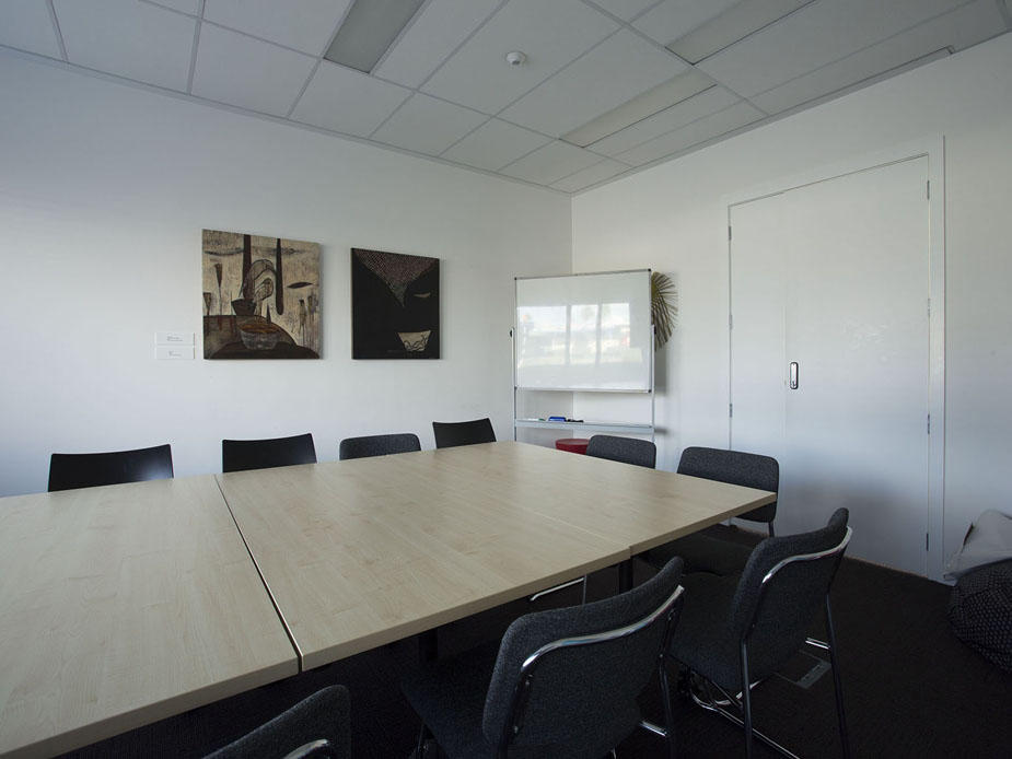 Meeting room with large table, chairs, whiteboard and artworks on wall