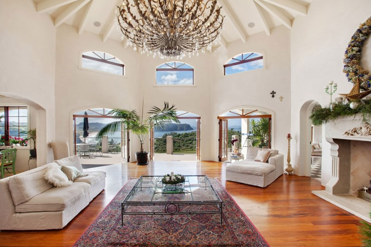 Grand living room with a vaulted ceiling, chandelier, arched French doors and timber floors