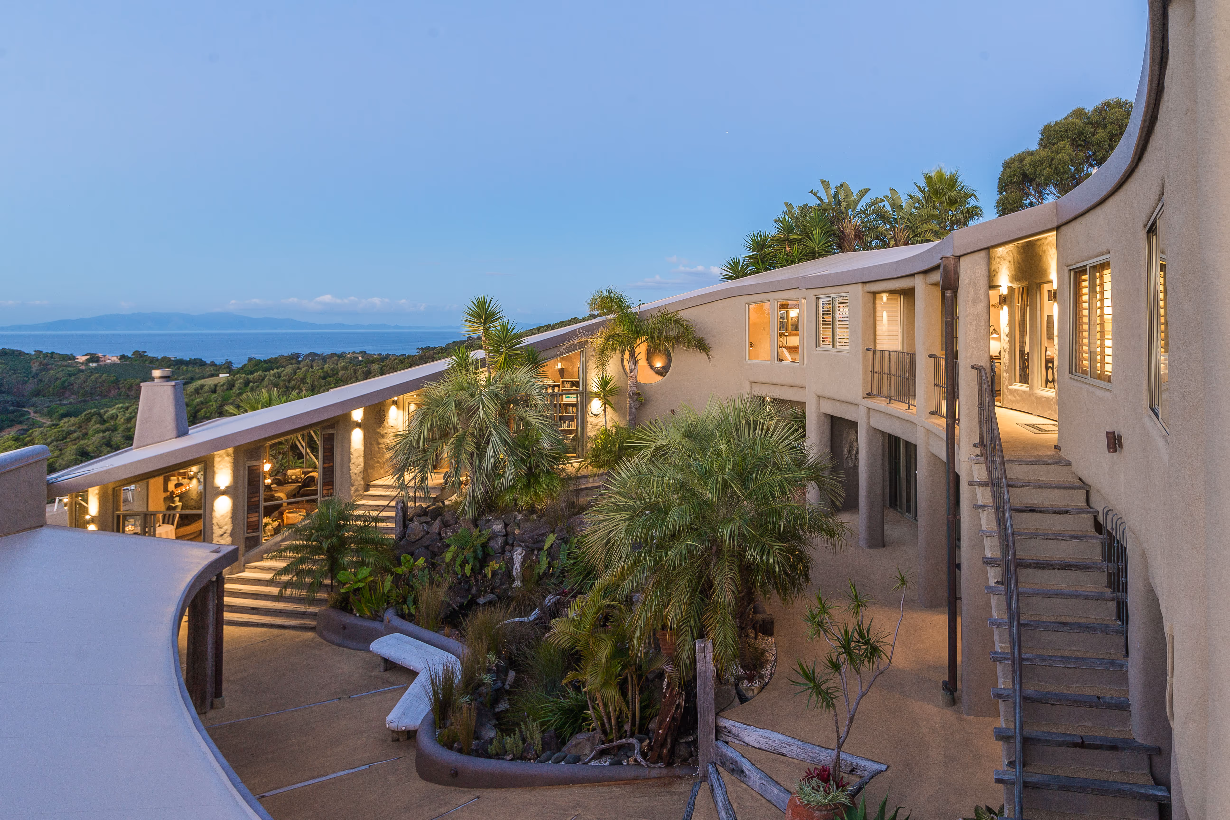 Lodge exterior at dusk with curved terrace walkway and tropical planting