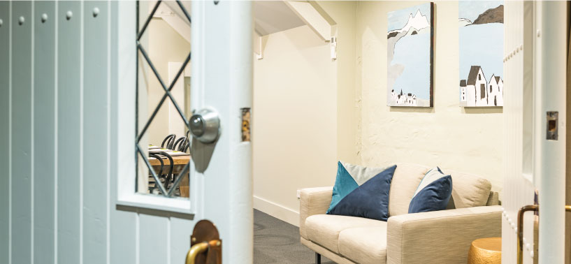 Hallway entrance with glazed Dutch door opening to cream lounge with coastal artwork