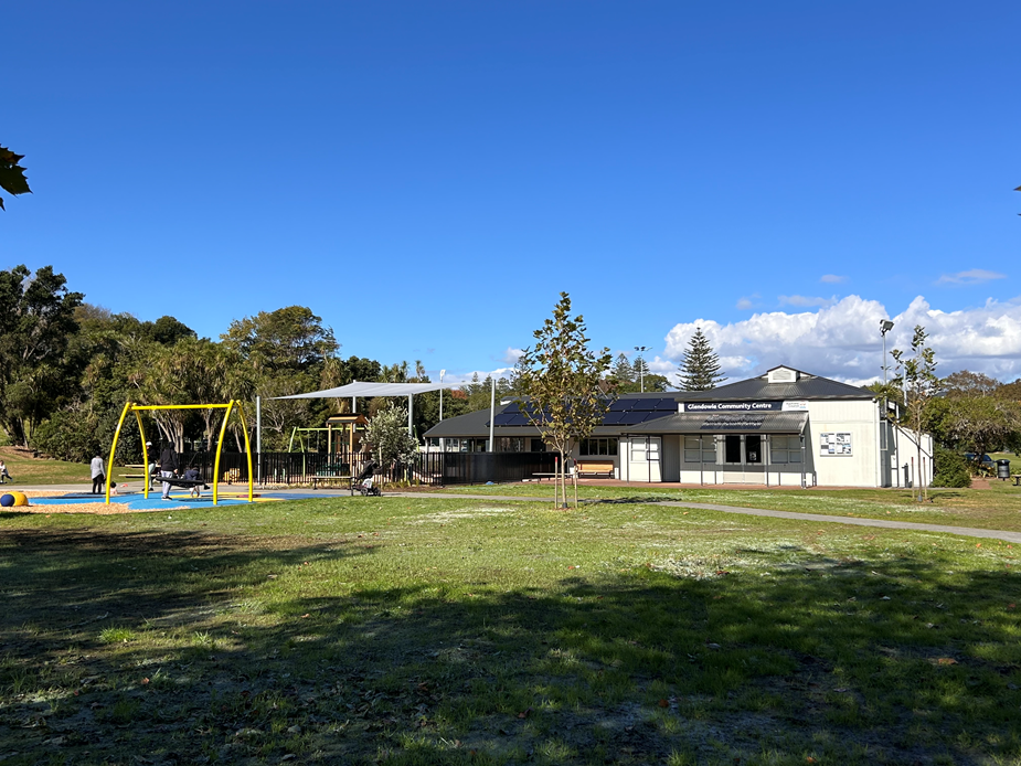 Modern white community centre building with park and playground beside