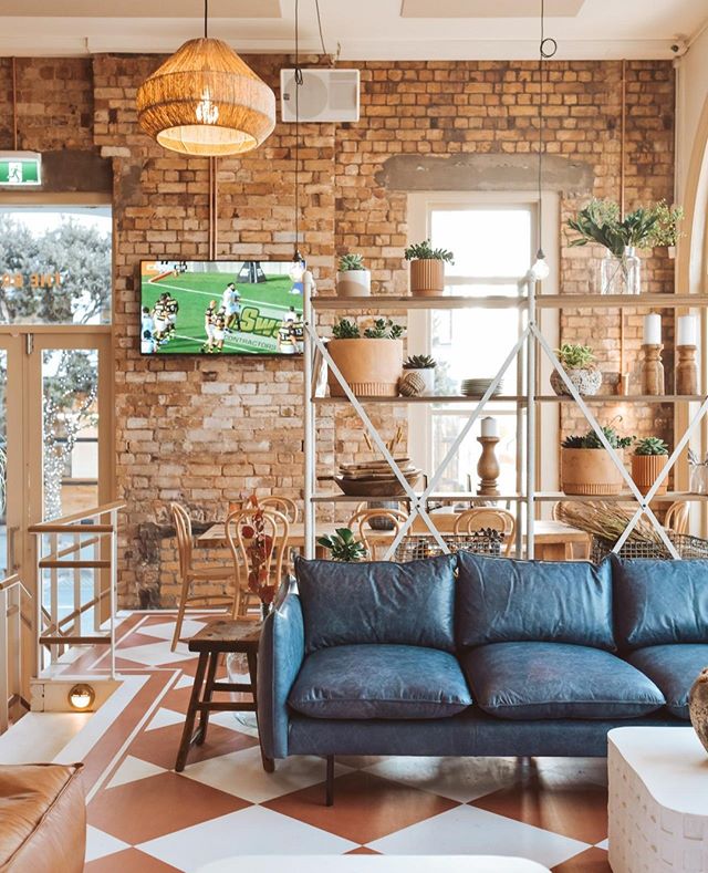 Pub interior with exposed brick, patterned floor tiles, blue sofa and shelving