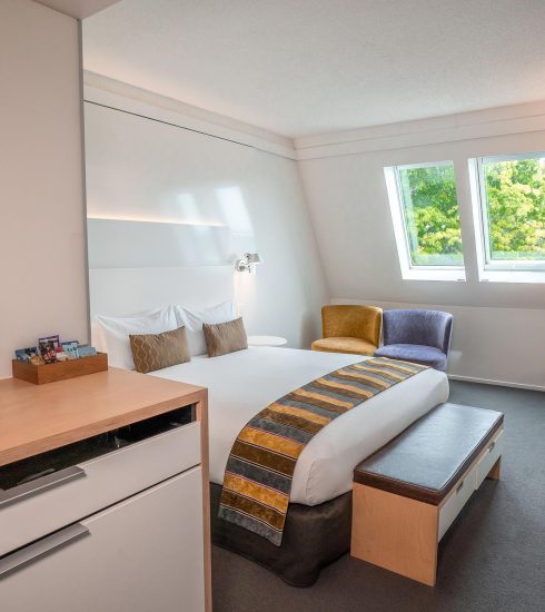 Hotel room with double bed, skylights and armchairs