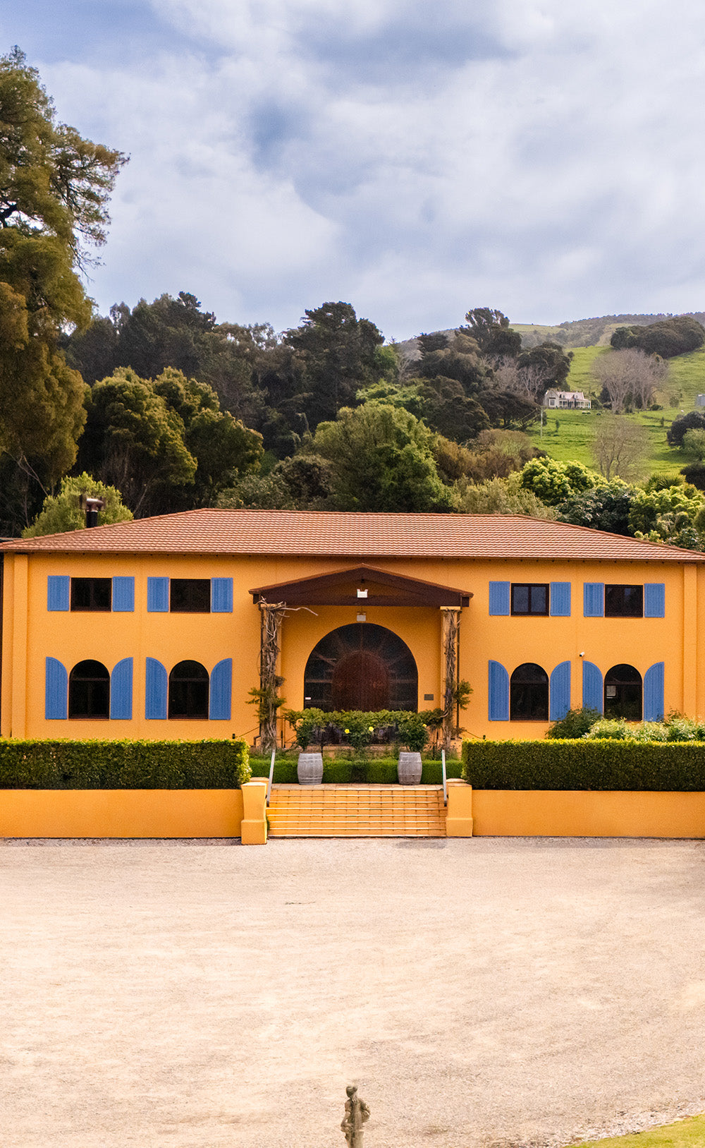Two-storey ochre winery building with blue shutters and arched entrance