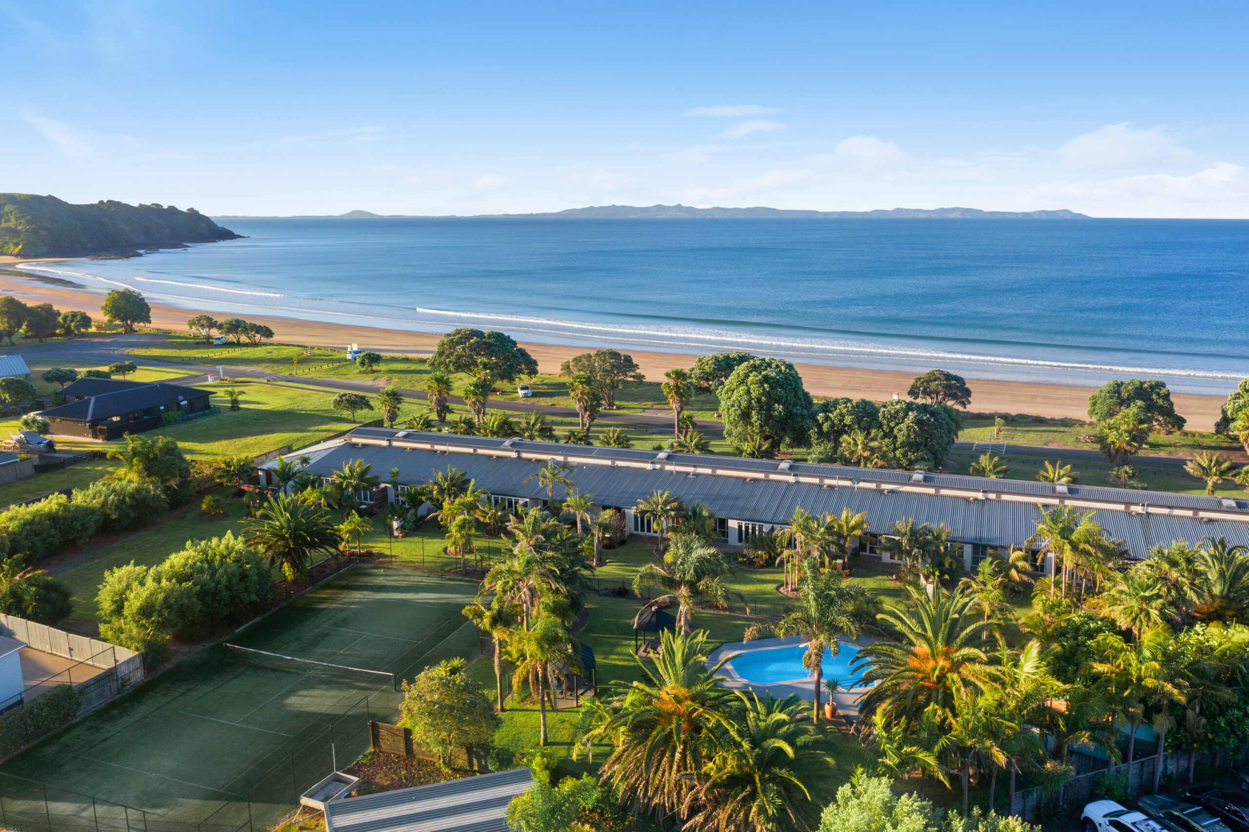 Aerial view of beachfront property with tennis court, pool, and grounds