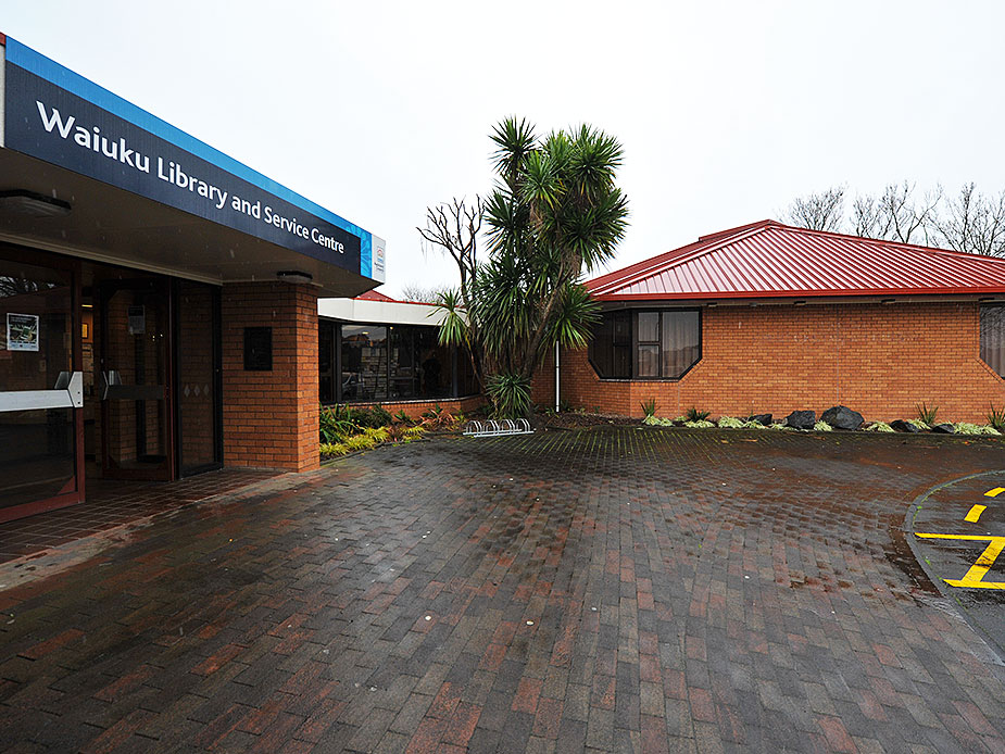 Brick hall and library building exterior with signage and wet paved courtyard
