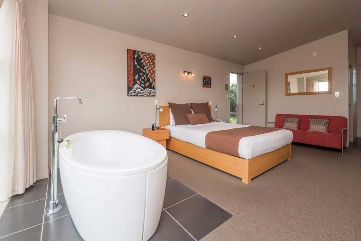 Suite with a freestanding bath, king bed and garden outlook through sliding doors