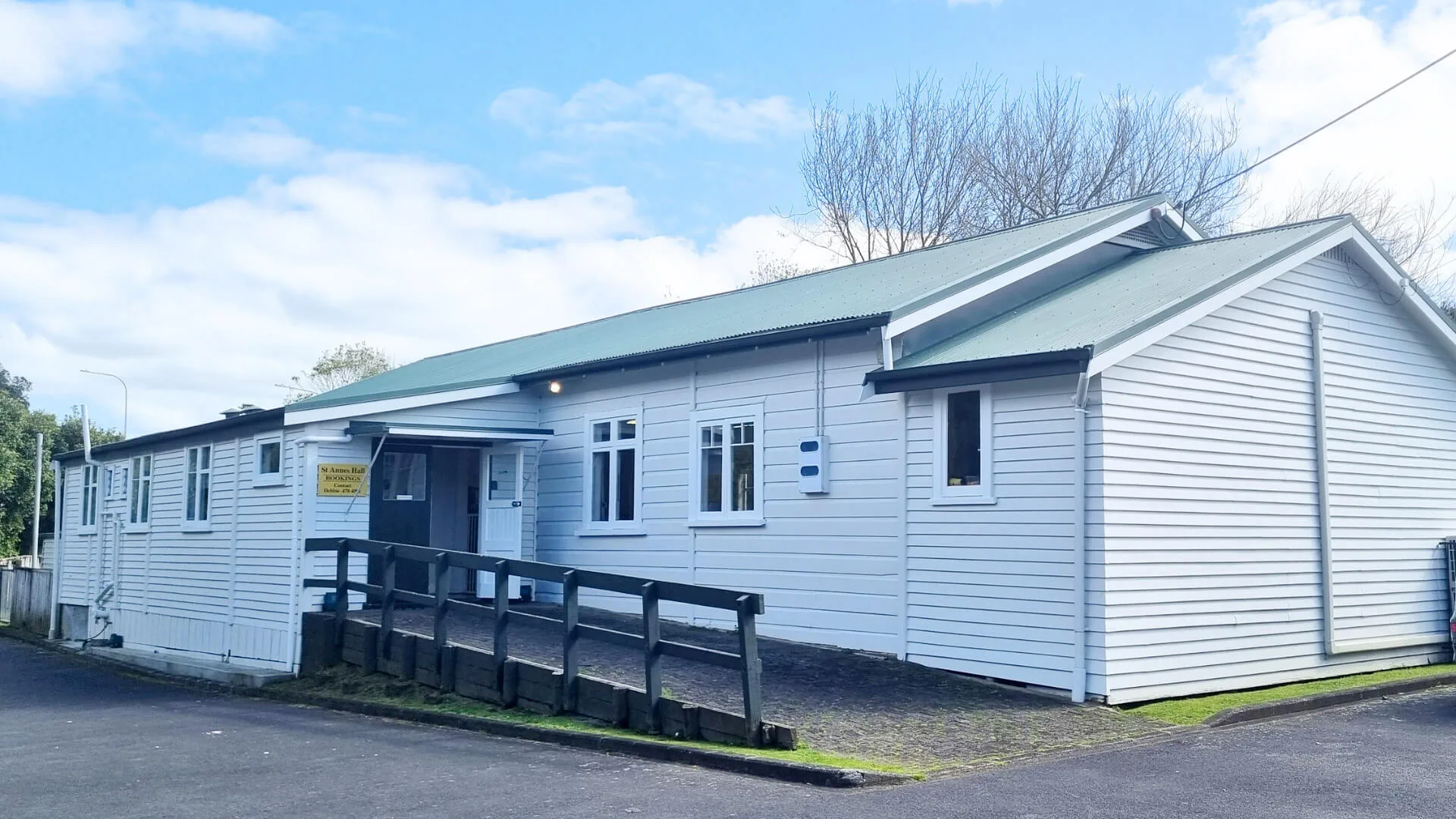 White weatherboard community hall exterior with green roof