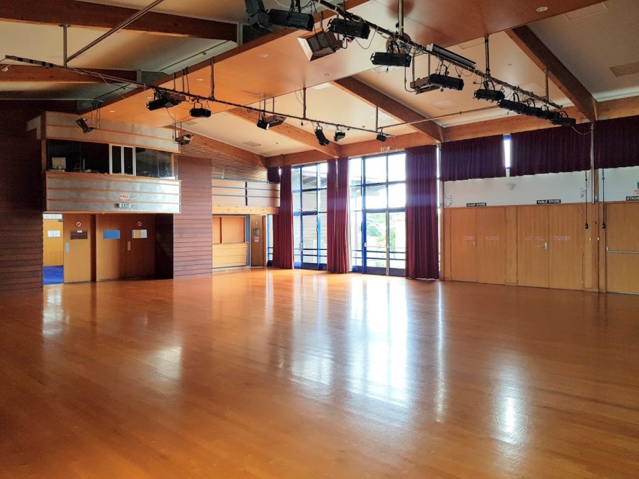 Large hall with timber ceiling, stage with closed curtain and open polished floor