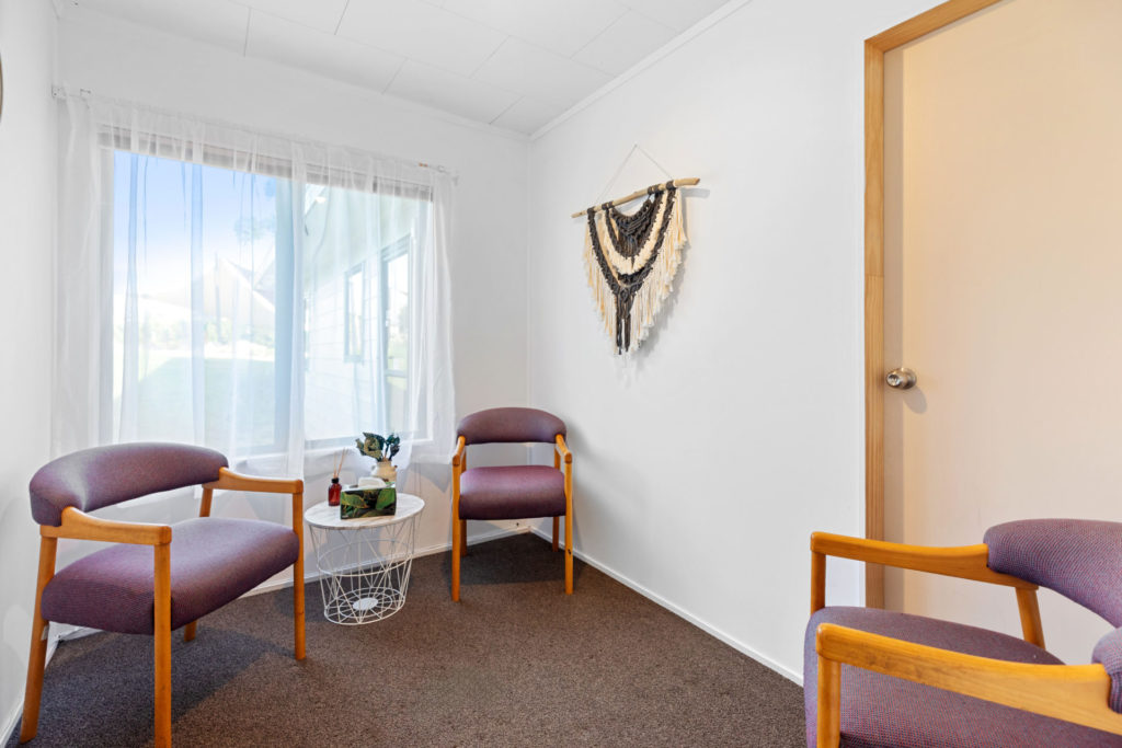 Small room with three armchairs, a side table, and a wall hanging decoration