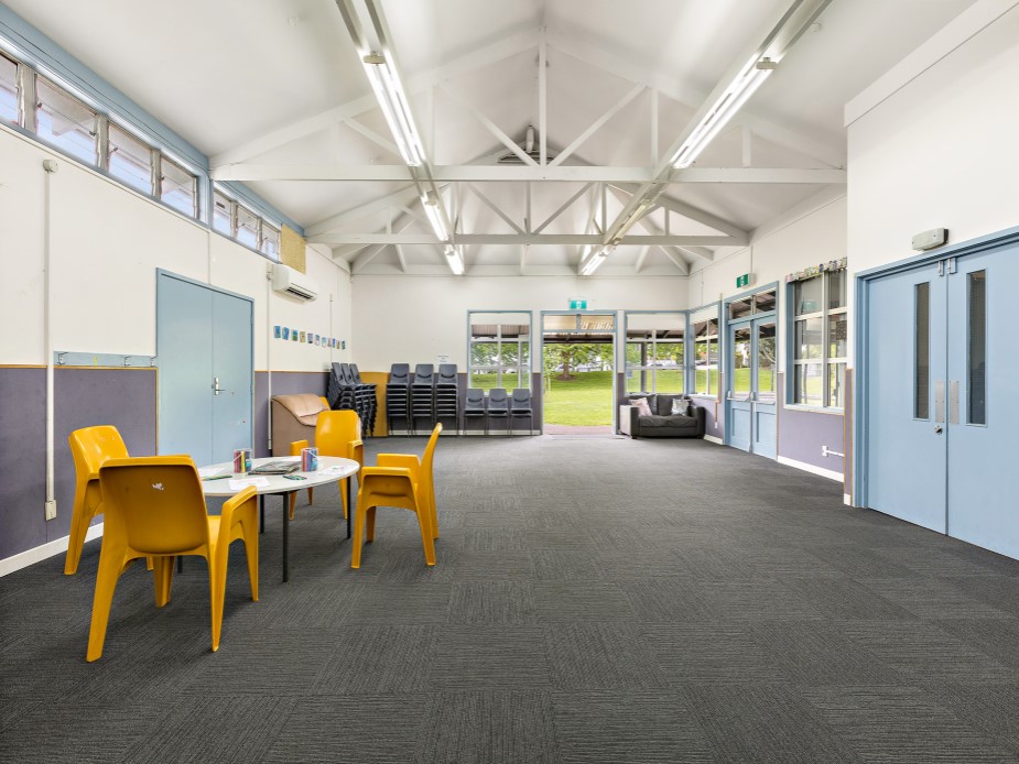 Hall room with vaulted ceiling, yellow plastic chairs and open outlook to park