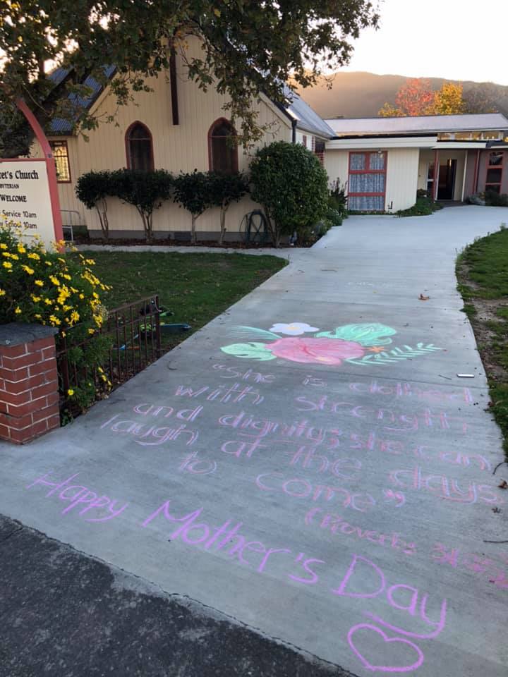 Church exterior showing chalk art on driveway with Mother's Day message