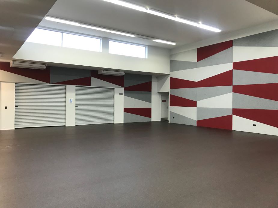 Empty hall with geometric red and grey painted walls and roller doors