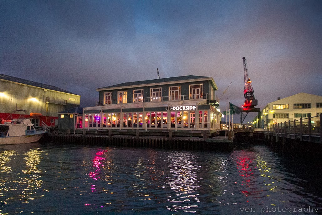 Dockside restaurant at night from the water, lit facade with reflections