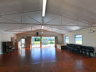 Hall main room with timber floor and stacked chairs along walls