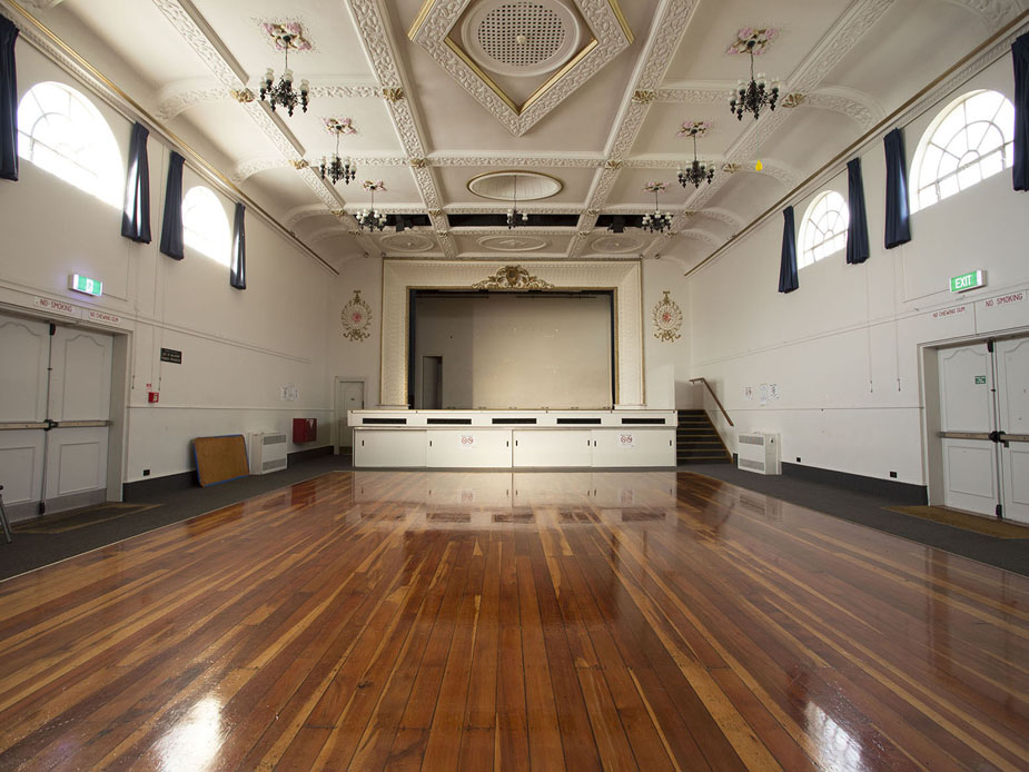 Grand hall with ornate ceiling, arched windows and polished timber floor