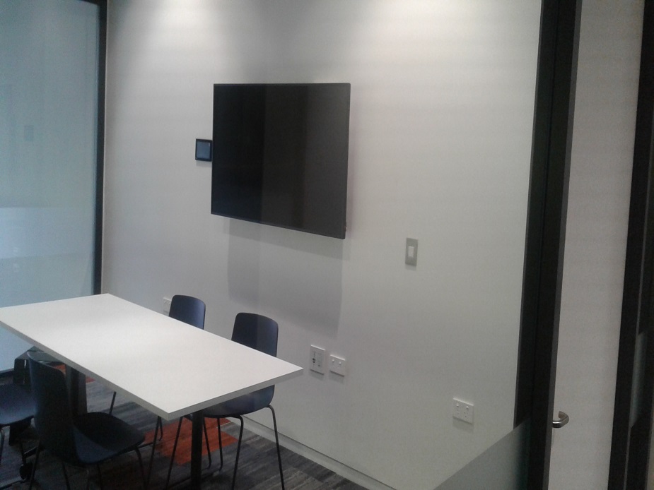 Small meeting room with table, chairs and wall-mounted screen