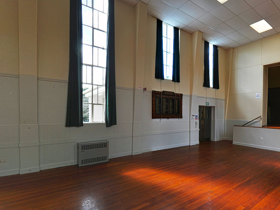 Hall interior with tall windows, timber floor and honour board on wall