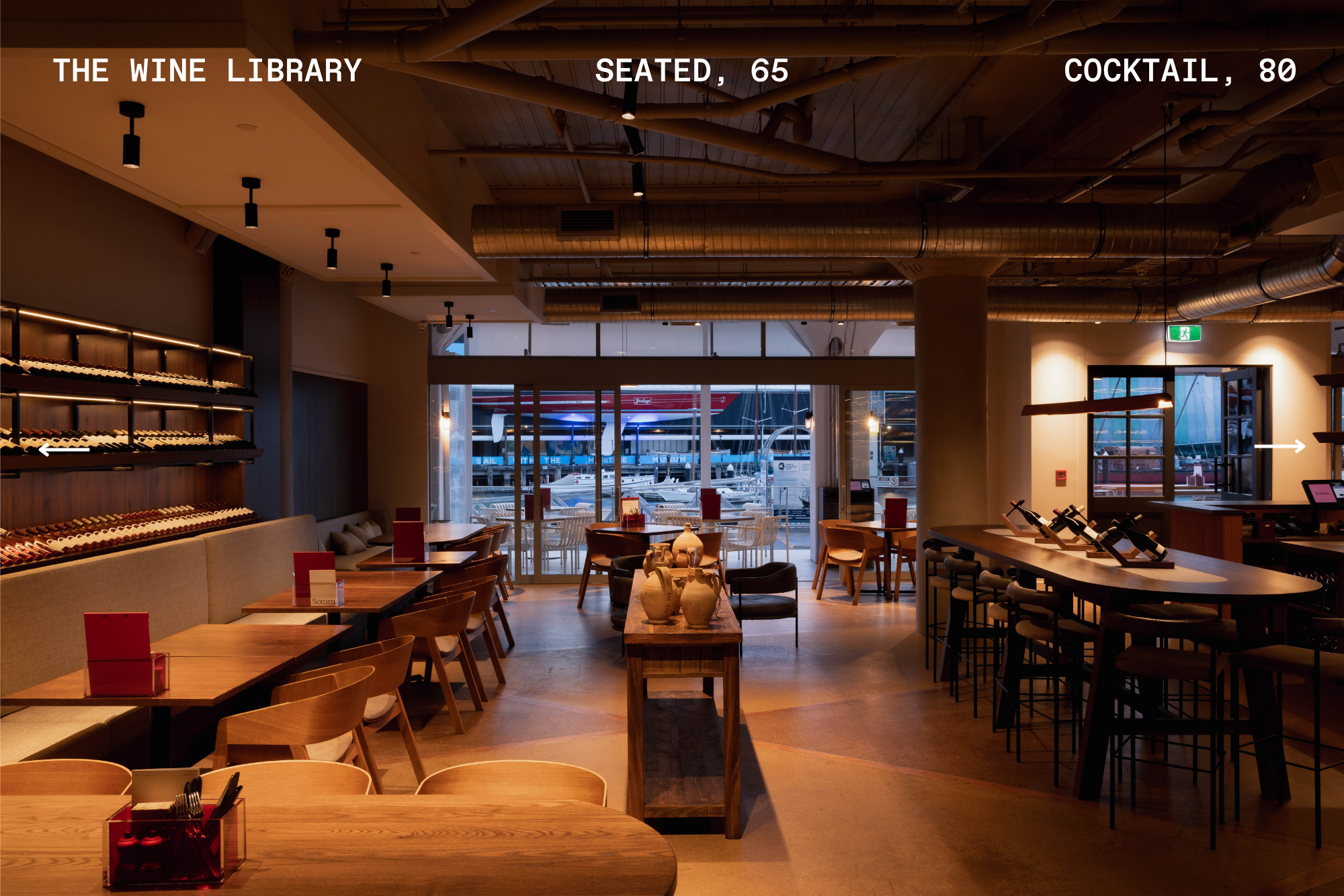 Industrial-style bar and dining room with wine shelves and text overlay showing capacity