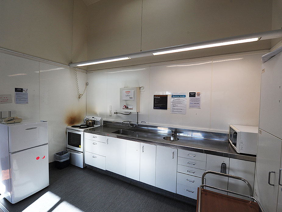 Plain community hall kitchen with stainless bench, fridge and microwave