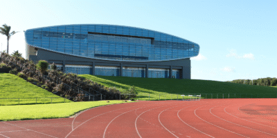 Modern glass arena building with running track in foreground