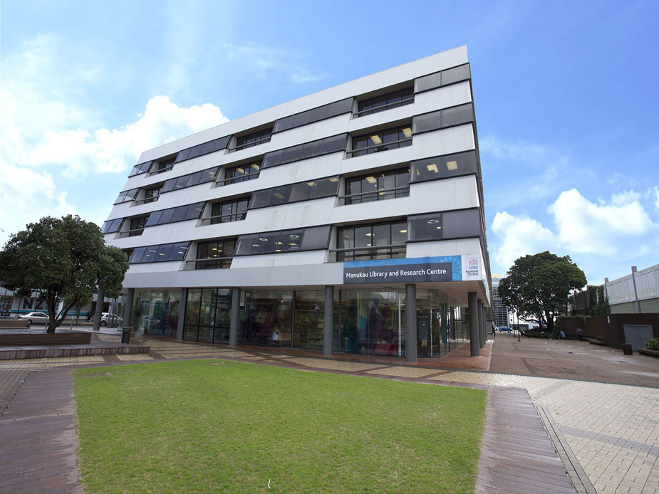 Multi-storey library building with white facade, glazed ground floor, and lawn forecourt