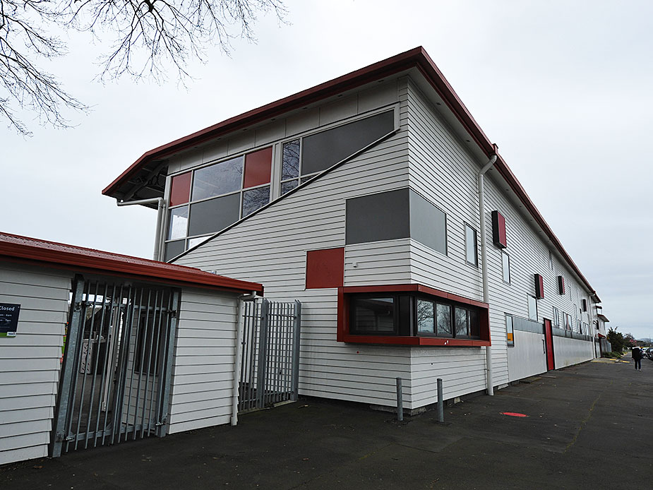 Side of grandstand building with white weatherboard cladding and red accents
