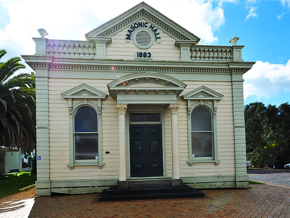 Cream weatherboard hall with classical columns, arched windows, and pediment facade dated 1883