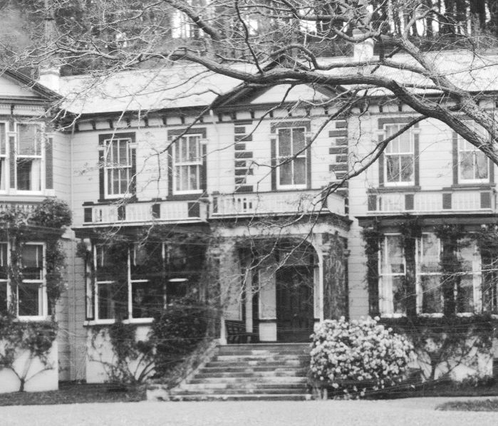 Black and white photograph of the homestead front entrance with stone steps and mature trees
