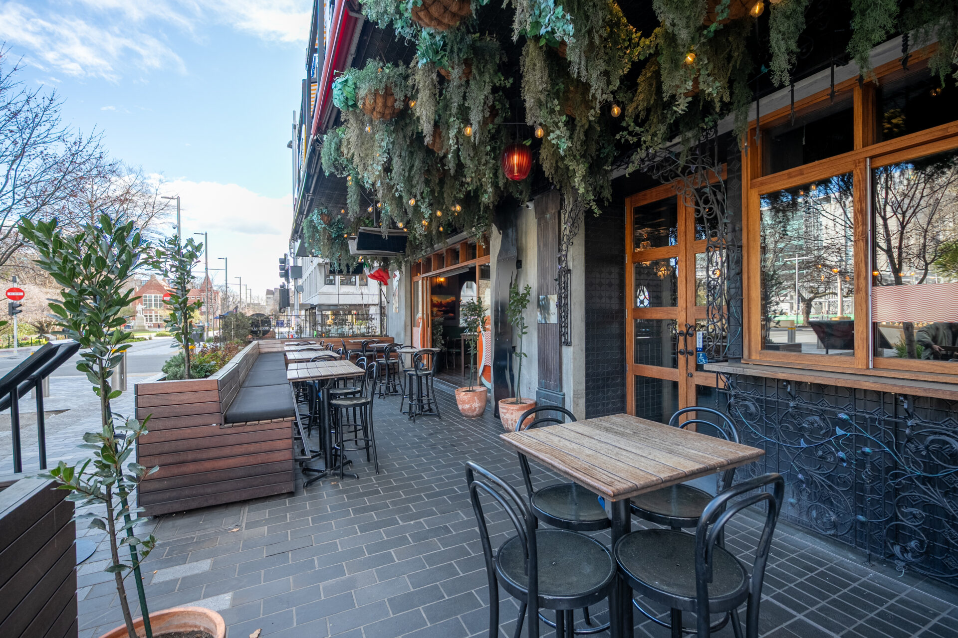 Restaurant facade with outdoor tables, hanging greenery, and timber-framed windows