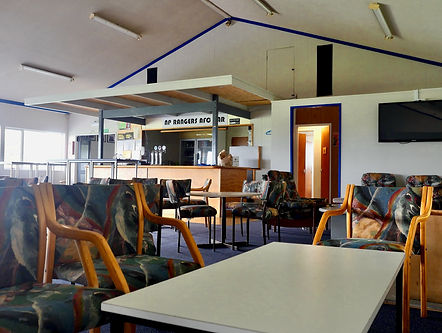 Clubroom interior with tables, chairs and bar counter visible in background