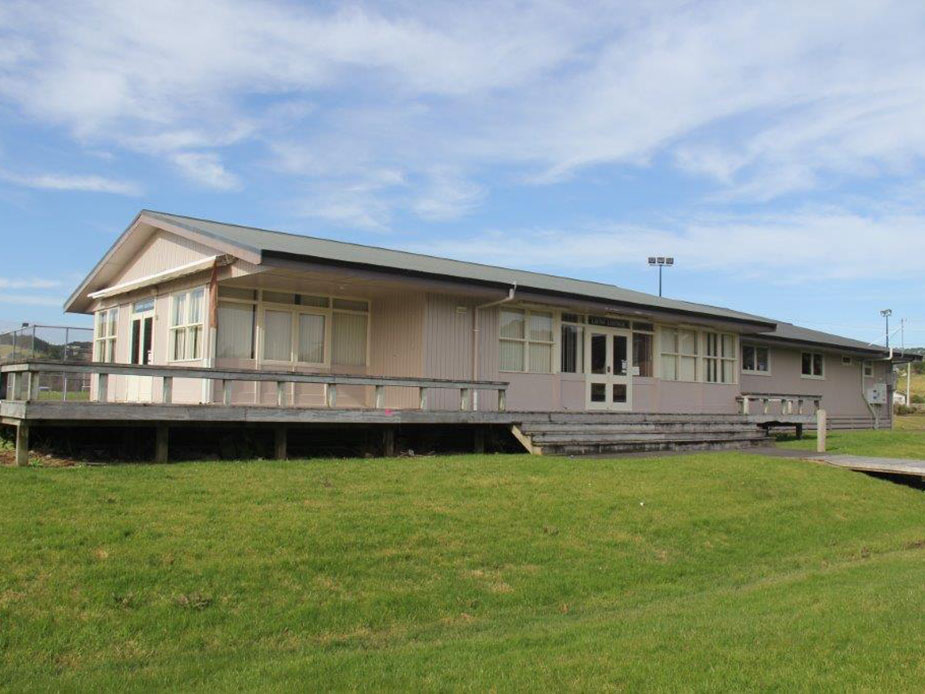 Side view of weatherboard lounge building with deck on green sports field