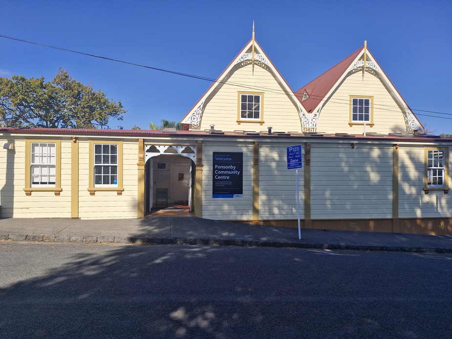 Cream weatherboard heritage hall with decorative gable trim, red roof and arched vehicle entrance
