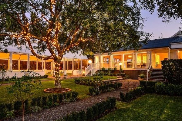 Estate homestead at dusk with fairy-lit trees and illuminated marquee