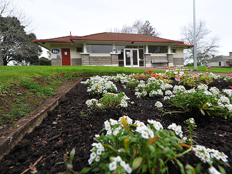 Low single-storey building with tiled roof, stone base and flower garden path