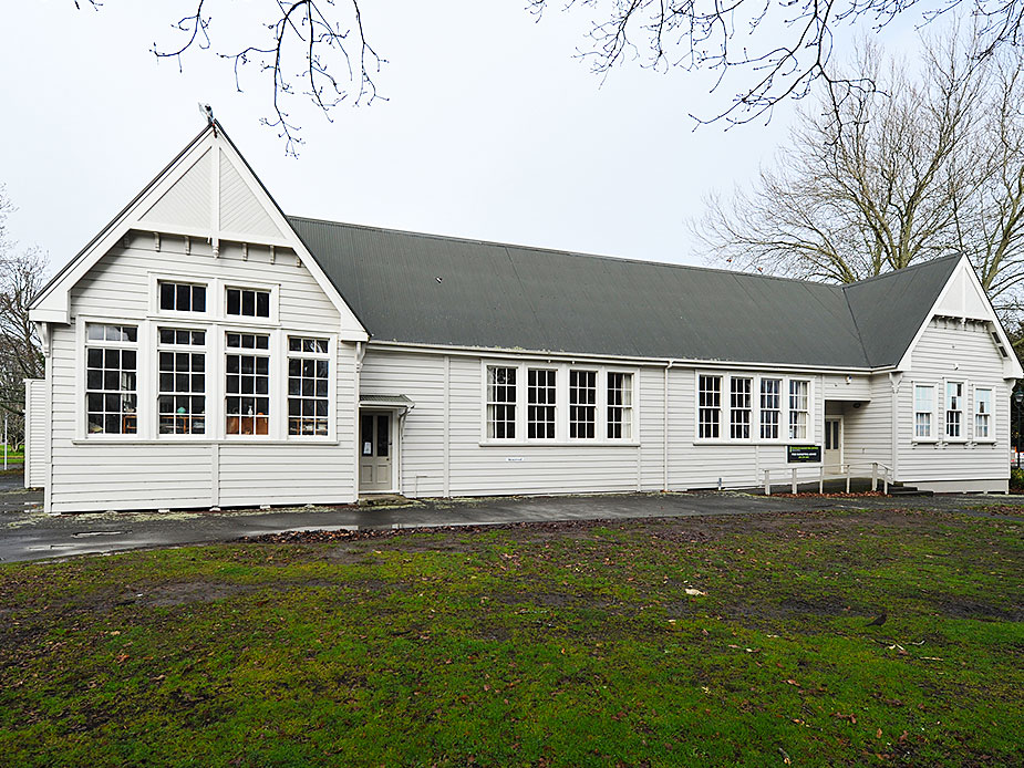 White weatherboard hall building with pitched roof and large windows