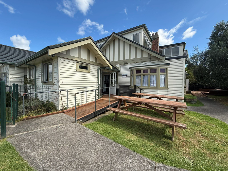 White timber community house exterior with deck and picnic tables on lawn