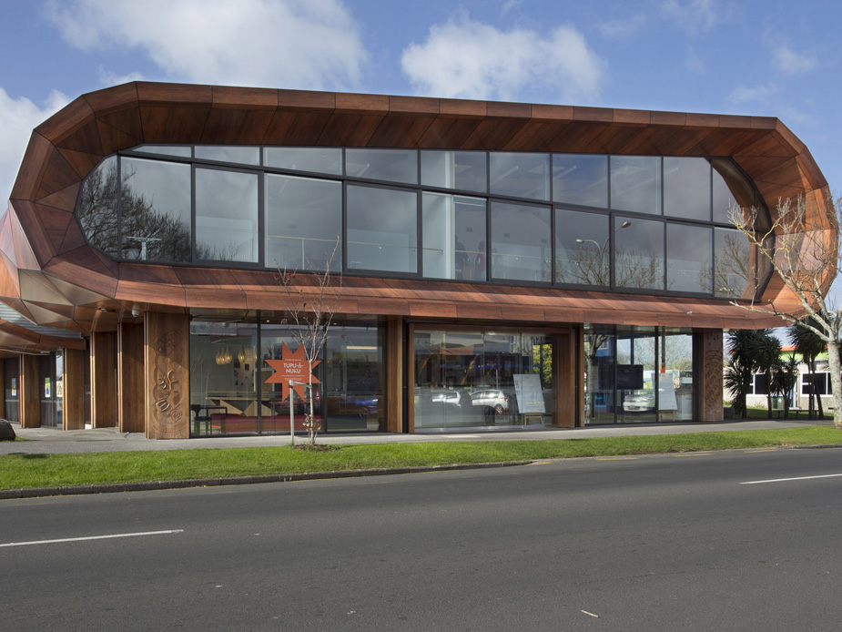 Two-storey timber-clad building with curved roofline, large glazed facade, street frontage