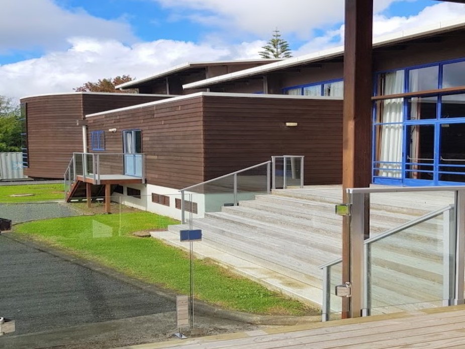Dark-timber cladding building with blue-framed windows and accessible stepped entry