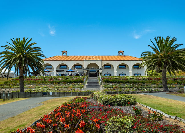 Spanish-style winery building with arched colonnade, red tile roof and formal gardens